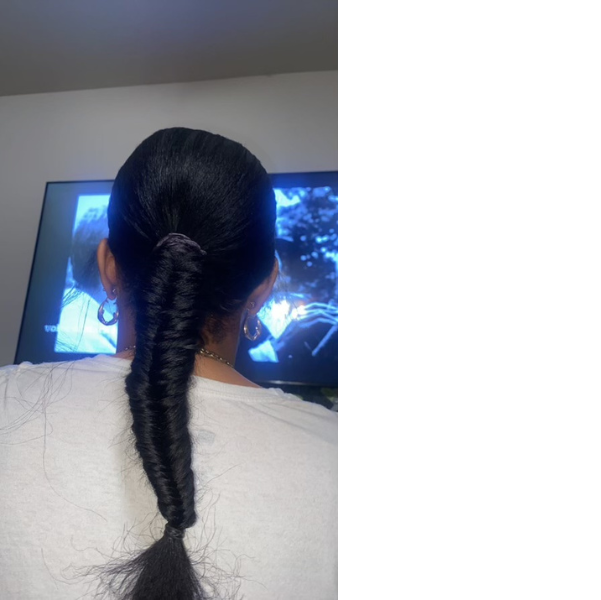 Low sleek bun on natural hair secured with a flower-shaped clip